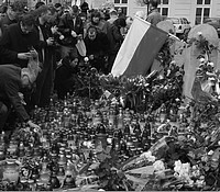 Ludzie tłumnie gromadzą się   na Krakowskim Przedmieściu. Palą znicze i składają kwiaty.