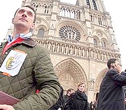 Młody katolik przed katedrą Notre Dame z napisem na kurtce